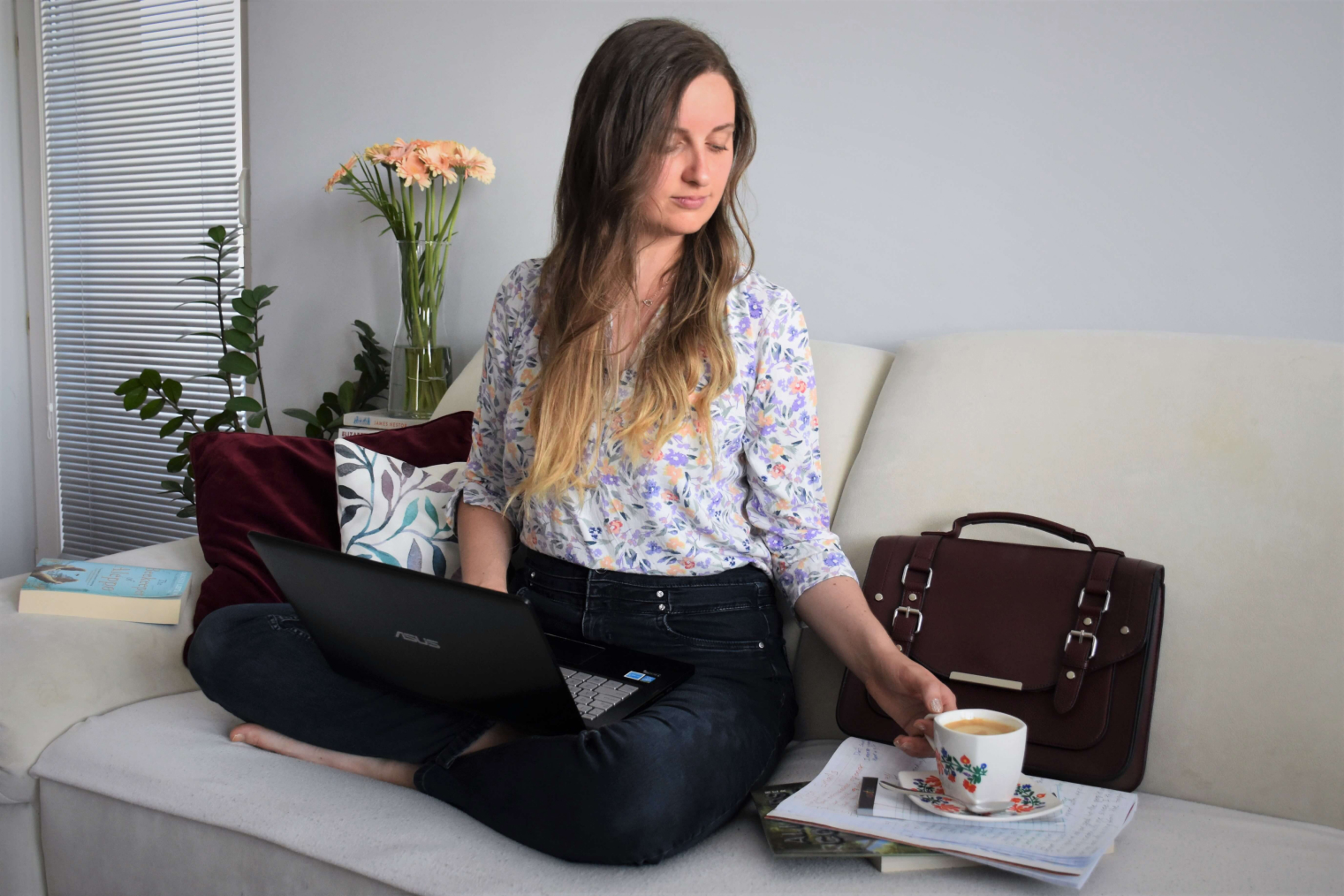 Katelyn is sitting in living room, working on her project and drinking coffe.