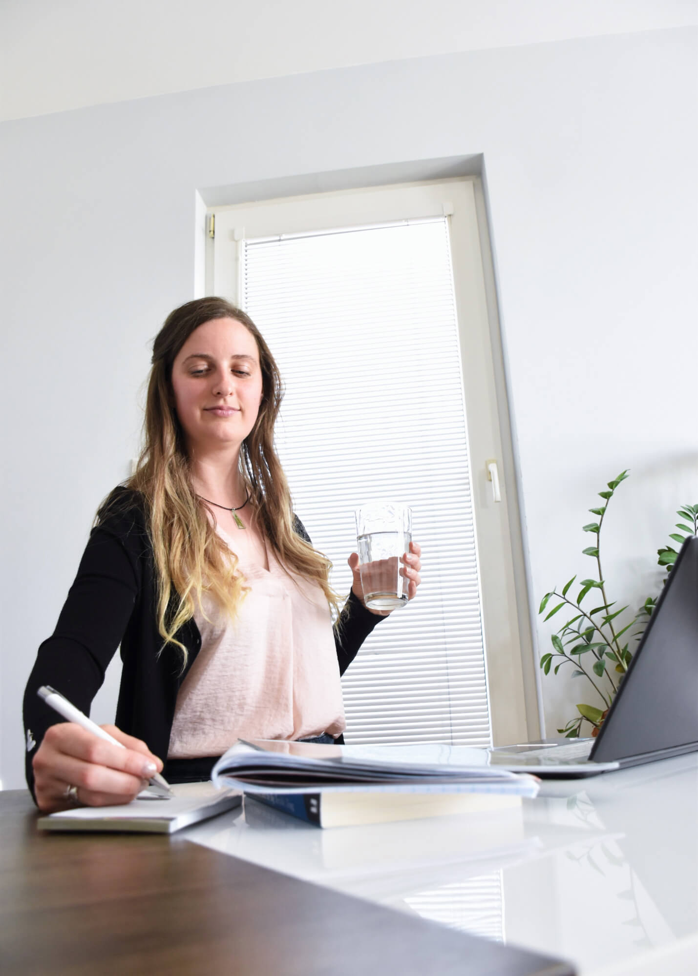 Katalyna is sitting in her office with a laptop and a glass of water in her right hand.
